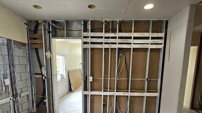 Steel stud framing and electrical rough in beside a block wall during a remodel, South Florida